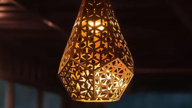 Lámpara colgante de latón calado con un patrón geométrico, encendida